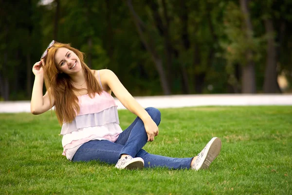 Schöne Frau sitzt auf dem grünen Rasen — Stockfoto