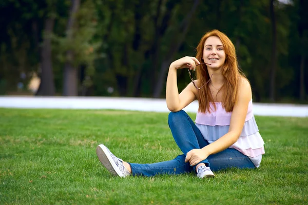 Schöne Frau sitzt auf dem Rasen im Park — Stockfoto