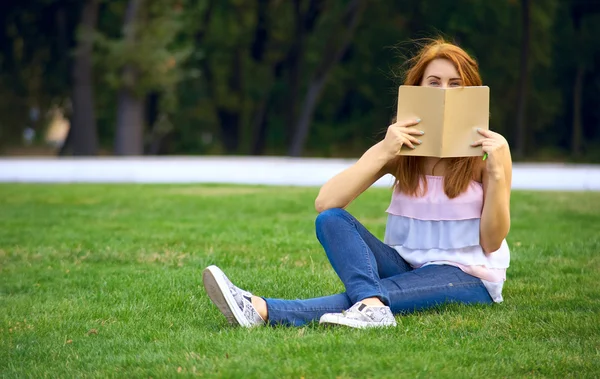 Hermosa mujer sentada en el césped en el parque — Foto de Stock