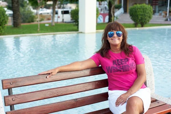 Mulher feliz adulto sentado em um banco no parque — Fotografia de Stock