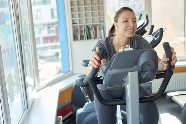 Vacker kvinna är utbildning på en stillastående cykel — Stockfoto