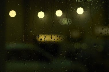Sokak lambalarıyla pencereye yağmur damlaları yağar