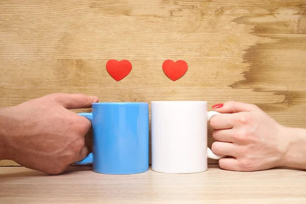 Hands loving couple holding cups with hearts — Stock Photo, Image
