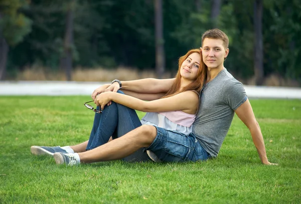 Jong koppel zittend op het grasveld in het park — Stockfoto