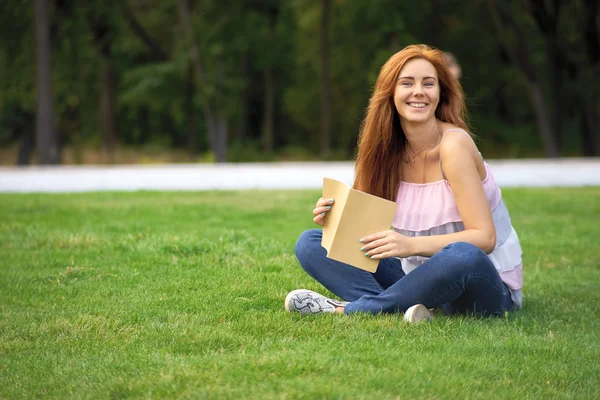 Жінка лежить на газоні з щоденником — стокове фото