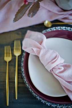 Pembe peçeteli, altın çatallı ve sonbahar yapraklı güzel bir masa.