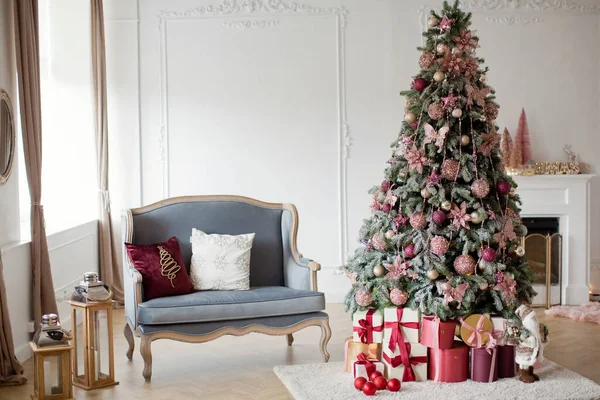 Gri kanepe ve Noel ağacıyla aydınlık bir Noel arifesi. Noel süslemeleri olan rahat bir oda.