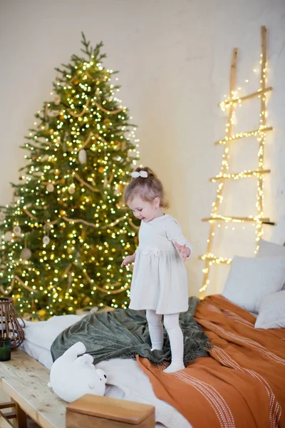 Cute Little Girl White Dress Stands Bed Christmas Tree Decorations — Stock Photo, Image