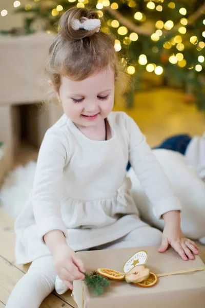 Cute Little Girl Białej Sukience Siedzi Pobliżu Choinki Dekoracji Świateł — Zdjęcie stockowe