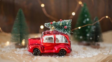 Noel ağacı olan küçük kırmızı bir araba. Noel konsepti, tatil teslimatı. Noel süslemeleri ve Noel ışıkları