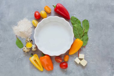 Renkli domatesli turta ve gri arka planda biber pişirmek için malzemeli fırın yemeği.