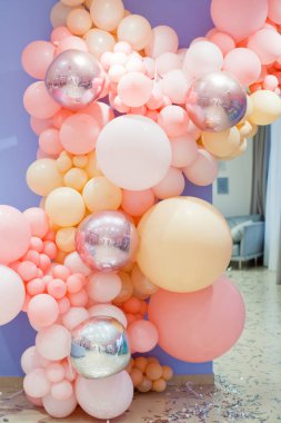 Renkli balonlar duvar süslemesi. Mor arka planda pembe, turuncu ve beyaz balonlar.