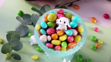 Pastel Easter decorations with bunny, colorful eggs candy on a light colorful background