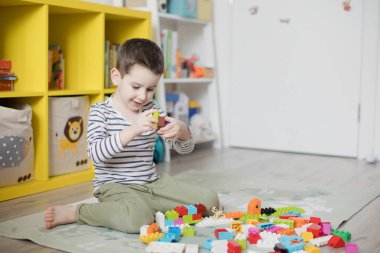 Beyaz çocuk odasında renkli oyuncak bloklarıyla oynuyor..