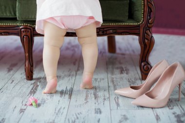 Küçük bebek bacakları ve kadın ayakkabıları. Pembe ayakkabılar ve küçük kız.