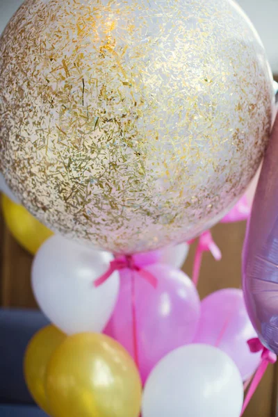 Pink and golden balloons with confetti. Birthday party for little girl