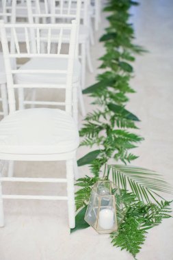 Botanik düğününde düğün töreni. Beyaz sandalyeler, mumlu cam vazolar ve tropik palmiye yaprakları.