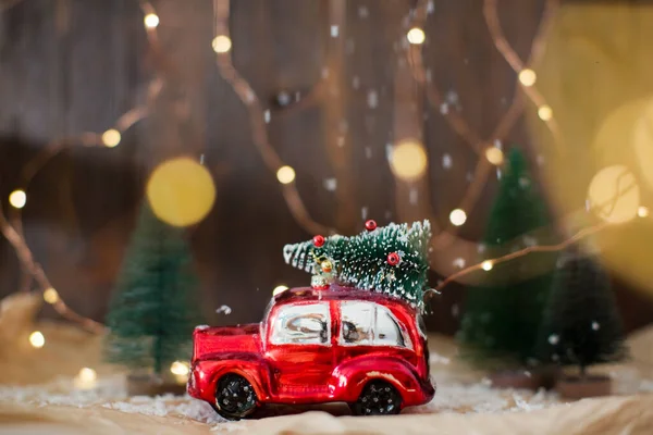 Noel ağacı olan küçük kırmızı bir araba. Noel konsepti, tatil teslimatı. Noel süslemeleri ve Noel ışıkları