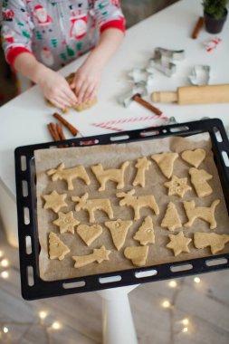 Noel pişirme geçmişi: Hamur, kurabiye kesme, baharatlar ve Noel süslemeleri. Siyah bir tepside Noel kurabiyeleri