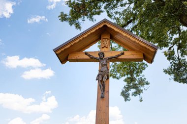 Koridor, mavi bulutlu gökyüzü ve dalların önünde İsa ile kesişiyor.