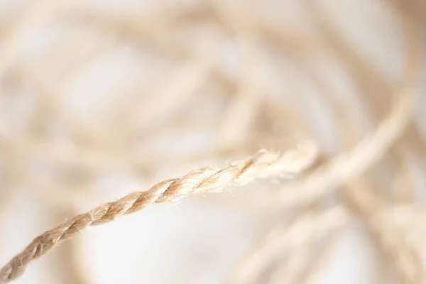 Chunky twisted sisal yarn in flat detail of a rope art separated by focal difference from the rest of the messy yarn and out of focus in the background