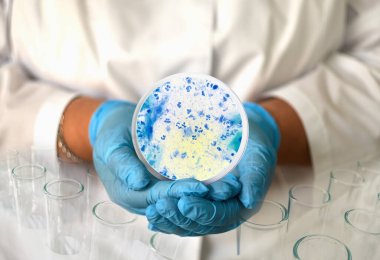 a girl in a medical gown and gloves holds a photo of Trichomonas from a microscope in a round frame. clipart