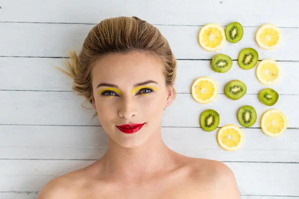 Sarışın kadın dilim limon ve kivi yanındaki döşeme — Stok fotoğraf