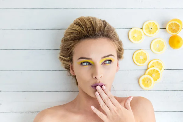 Donna bionda sdraiata accanto a fette di limone — Foto Stock