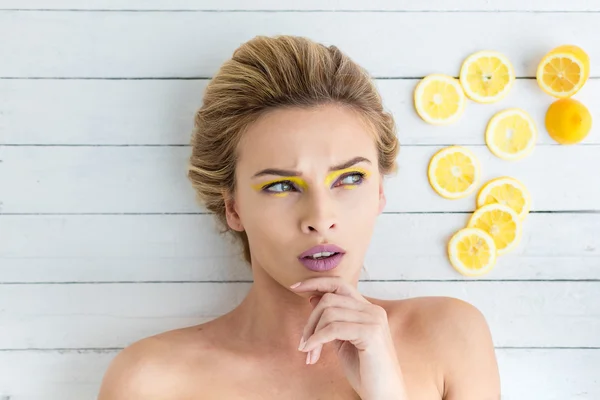 レモンのスライスの横に敷設する金髪の女性 — ストック写真