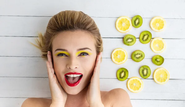 Sarışın kadın dilim limon ve kivi yanındaki döşeme — Stok fotoğraf