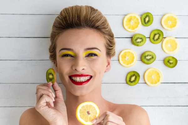 Blondine liegt neben Zitronen- und Kiwi-Scheiben — Stockfoto