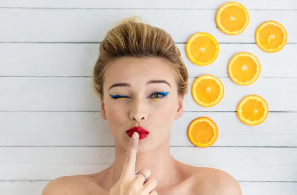 Blonde vrouw leggen naast segmenten van Oranje — Stockfoto