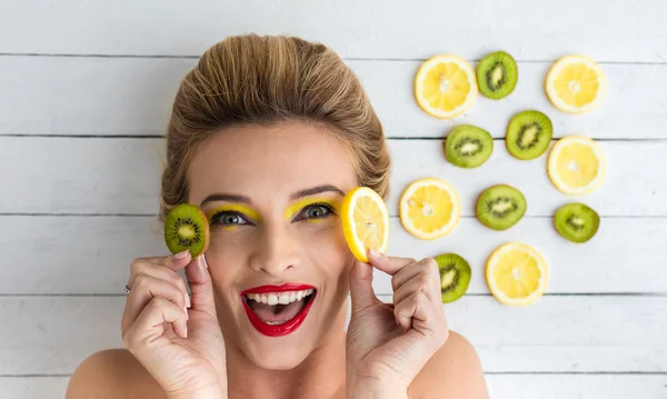 Blondine liegt neben Zitronen- und Kiwi-Scheiben — Stockfoto