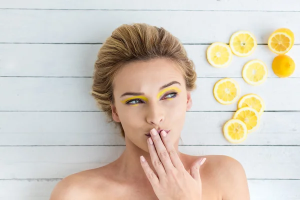 Mulher loira que coloca ao lado de fatias de limão — Fotografia de Stock