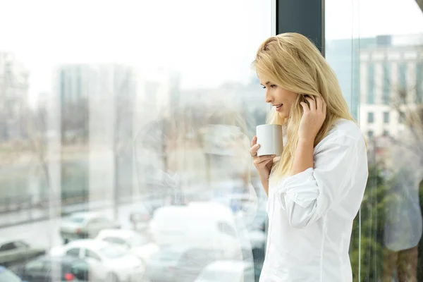 Hermosa mujer rubia al lado de una ventana — Foto de Stock