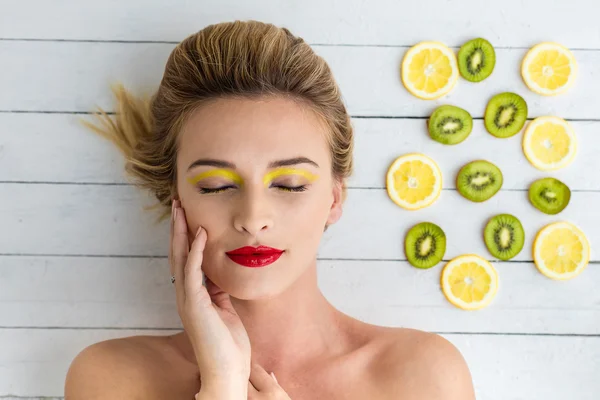 Donna bionda sdraiata accanto a fette di limone e kiwi — Foto Stock