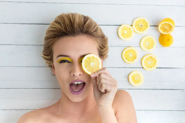 Blonde woman laying next to slices of lemon — Stock Photo, Image