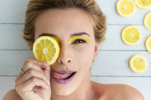 Blonde woman laying next to slices of lemon — Stock Photo, Image