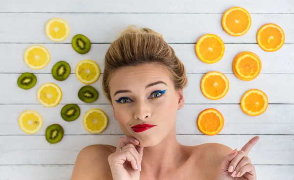 Blonde vrouw leggen naast segmenten van sinaasappel, citroen en kiwi — Stockfoto