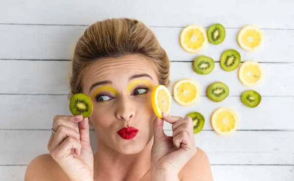 Sarışın kadın dilim limon ve kivi yanındaki döşeme — Stok fotoğraf