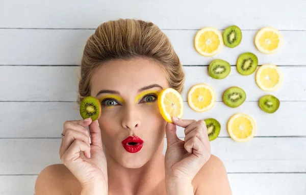 Blonde vrouw leggen naast de plakjes citroen en kiwi — Stockfoto