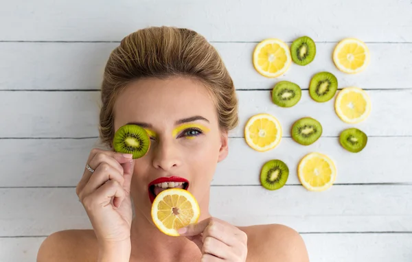 Blondine liegt neben Zitronen- und Kiwi-Scheiben — Stockfoto