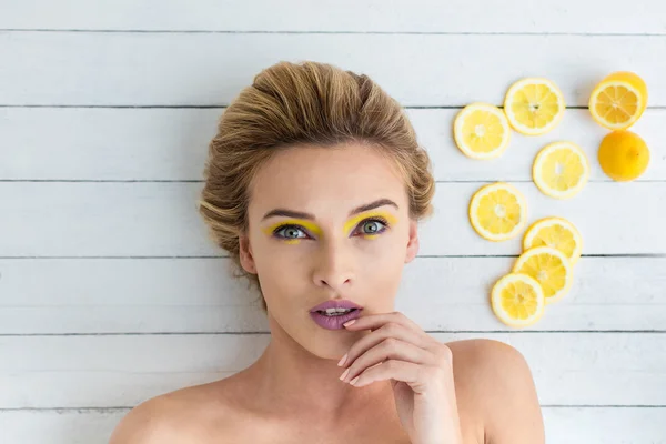 Blonde vrouw leggen naast de plakjes citroen — Stockfoto
