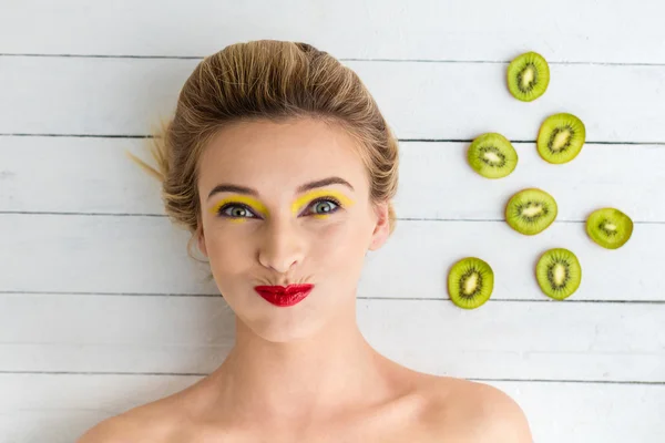 Blond kvinna om bredvid skivor av kiwi — Stockfoto