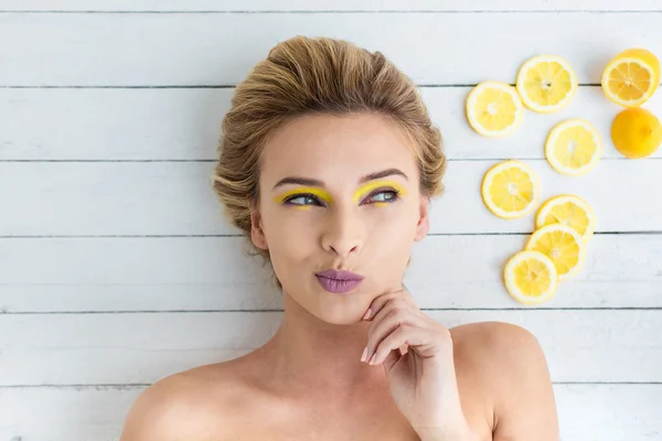 Donna bionda sdraiata accanto a fette di limone — Foto Stock
