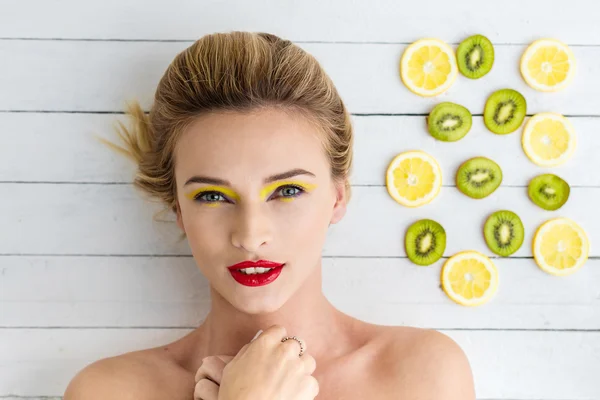 Sarışın kadın dilim limon ve kivi yanındaki döşeme — Stok fotoğraf