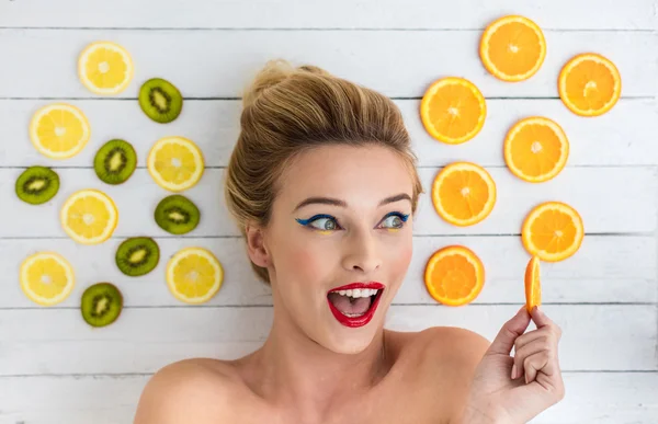 Blondýnka, kterým se vedle plátky pomeranče, citronu a kiwi — Stock fotografie