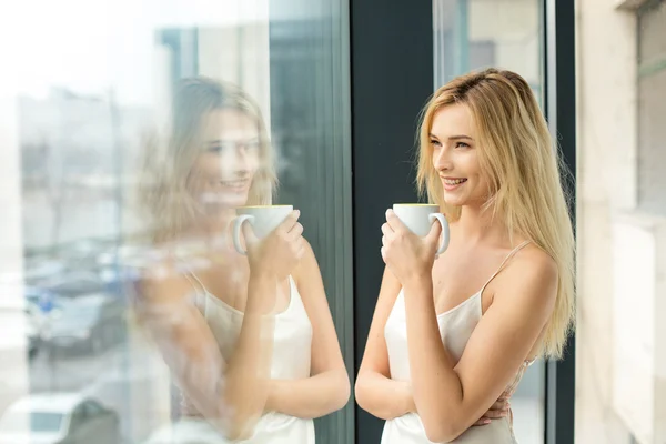 Mooie blonde vrouw naast een venster — Stockfoto