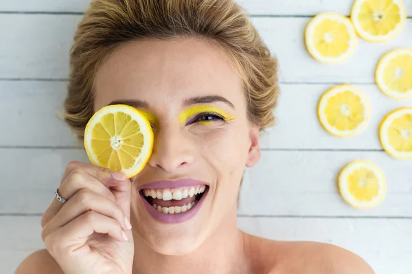 Blonde woman laying next to slices of lemon — Stock Photo, Image