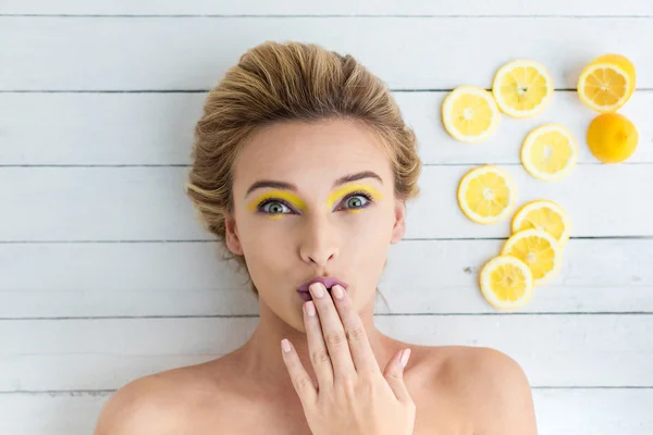 Donna bionda sdraiata accanto a fette di limone — Foto Stock